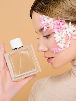 attractive-woman-with-flowers-on-face-looking-at-bottle-of-perfume-isolated-on-beige.jpg